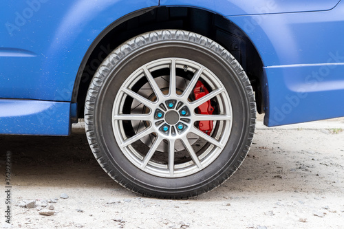 Stylish blue car wheel with red brake caliper and five-nut rim. Brake system support