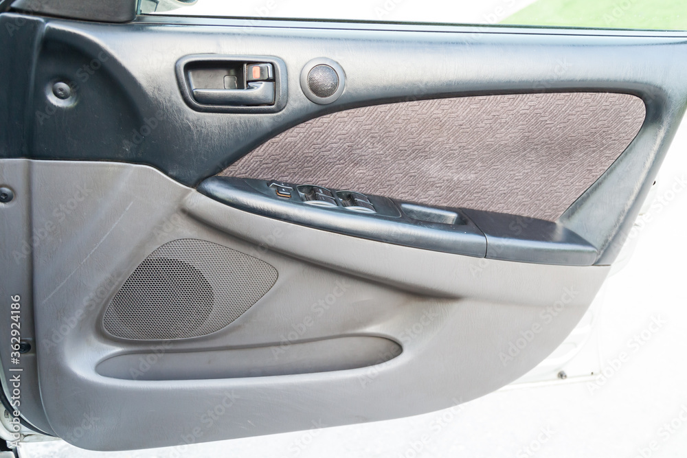 Closeup of a black door with gray plastic trim and a brown fabric insert inside the interior of a Japanese car after dry cleaning. Panel repair in a car service.
