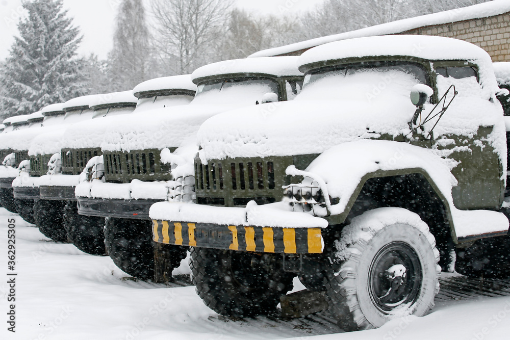 Soviet and Russian military trucks stand in a row in winter under the snow. Military russian green army vehicle.