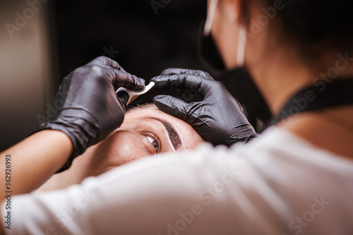 Girl artist paints an eyebrow tattoo. The process of tattooing. Permanent makeup