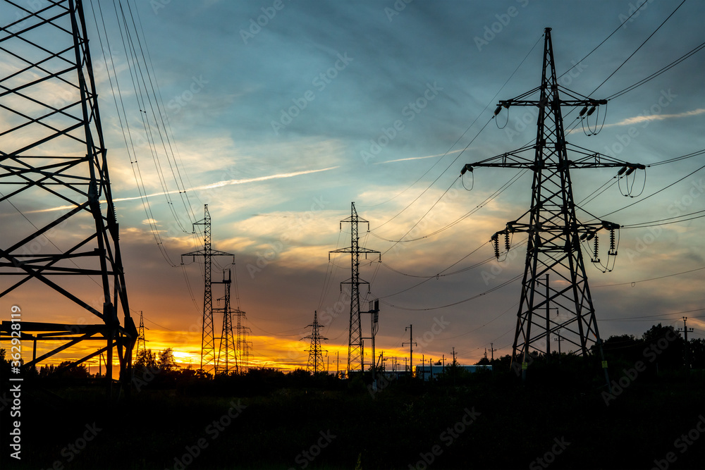 Two high-voltage lines in one corridor of power lines against the background of the evening sky and sunset.