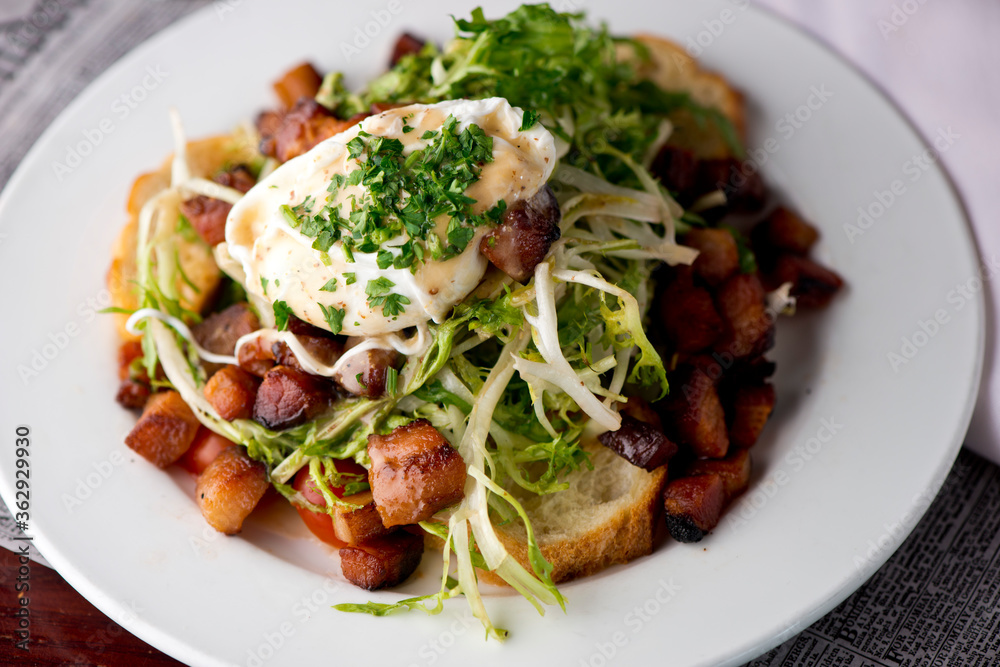 Salad. Frisee lettuce dress with olive oil and balsamic vinegar and topped with bacon lardons a fried egg and garnished with italian parsely and a toasted baguette. Served in a French Bistro. Salad. Frisee lettuce dress with olive oil and balsamic vinegar and topped with bacon lardons a fried egg and garnished with italian parsely and a toasted baguette. Served in a French Bistro.
