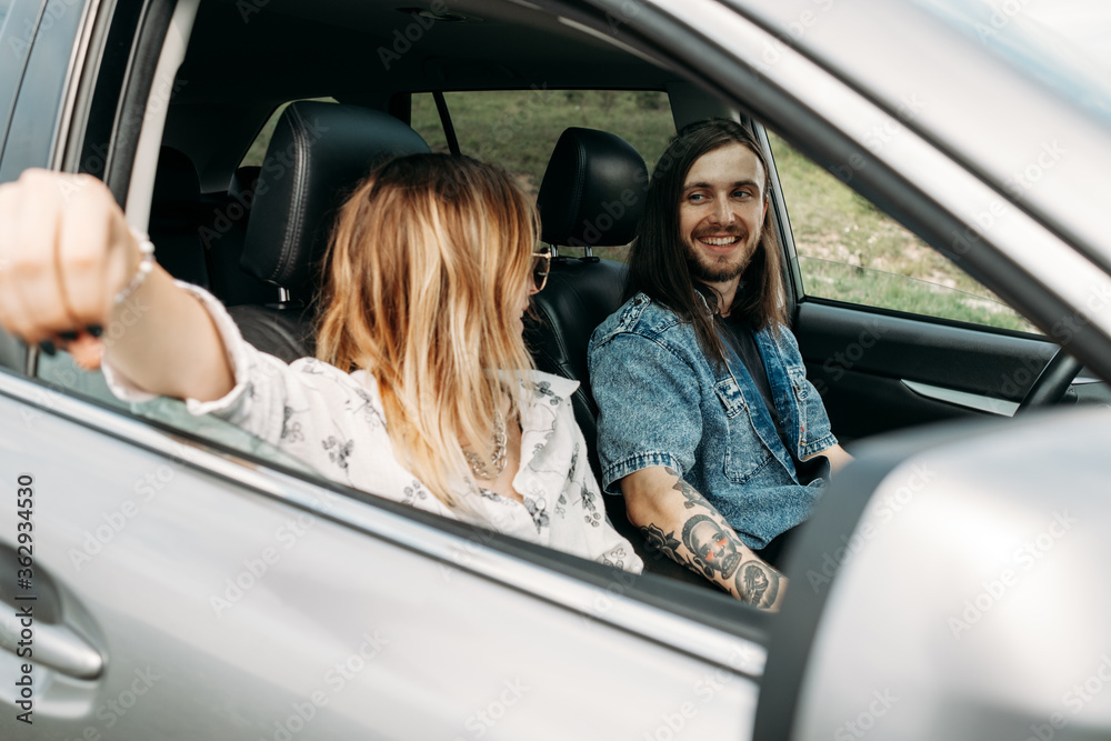 Young Stylish Traveling Hipsters Having Fun Sitting in Modern Car, Travel and Road Trip Concept Young Stylish Traveling Hipsters Having Fun Sitting in Modern Car, Travel and Road Trip Concept