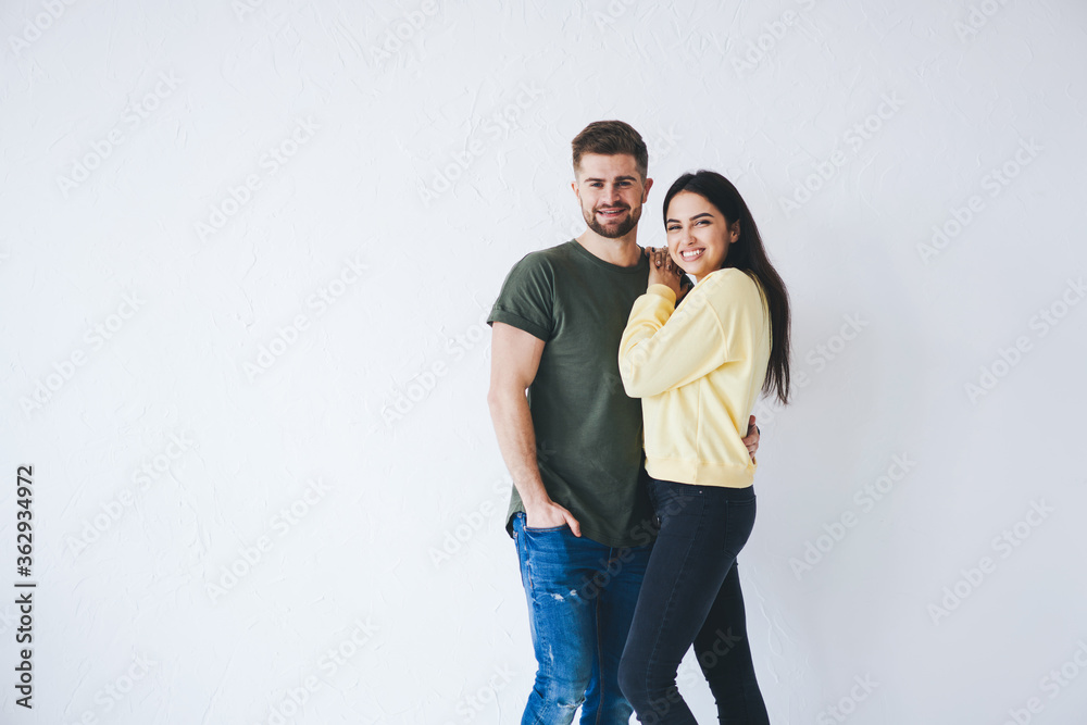 Half length portrait of young male and female couple in love dressed in casual outfit feeling happy of relationship standing on white background with copy space area for your advertising content