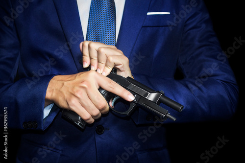 Close up of gunman in business man suit holding pistol in hands.