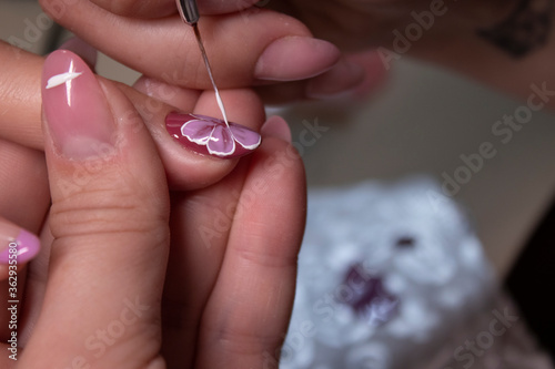 the process of doing manicure. Closeup of hands of professional manicurist  painting little flowers on nails. Concept of doing manicure. beauty concept. Gel polish  shellac