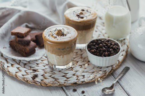 Fototapeta Naklejka Na Ścianę i Meble -  Glass of Iced Dalgona Coffee, trendy fluffy creamy whipped coffee and milk on white wooden background.