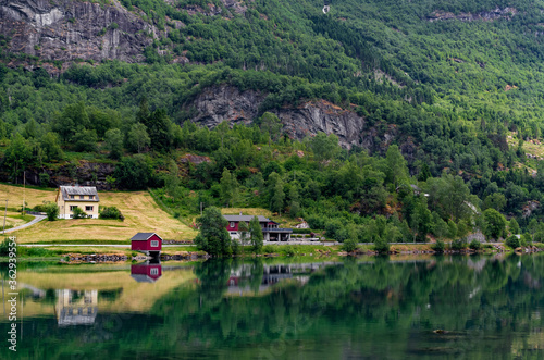 Beautiful Norwegian landscape reflected in mirror like water surface of a lake. Farm houses, forest, fields and mountains on a bank of the lake Floen, Oldedalen valley, Norway.