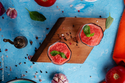  classic spanish raw eating cold soup Gazpacho served  in glasses around blue background. food recipe. healthy concept. photo