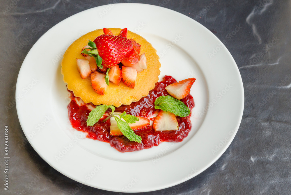 Homemade cheese cakes served with strawberry sauce made from organic strawberries. Topping with fresh organic strawberries and decorated with mint leaves. Homemade cheese cakes served with strawberry sauce made from organic strawberries. Topping with fresh organic strawberries and decorated with mint leaves.