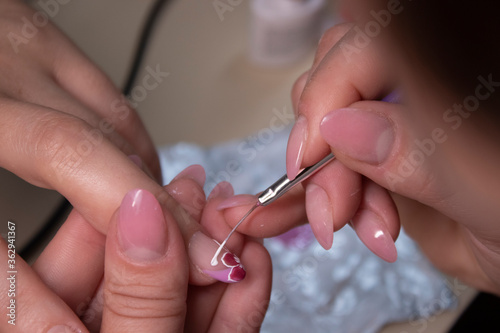 the process of doing manicure. Closeup of hands of professional manicurist, painting little flowers on nails. Concept of doing manicure. beauty concept. Gel polish, shellac