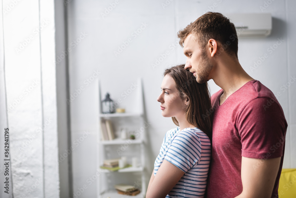 sad beautiful young couple hugging at home