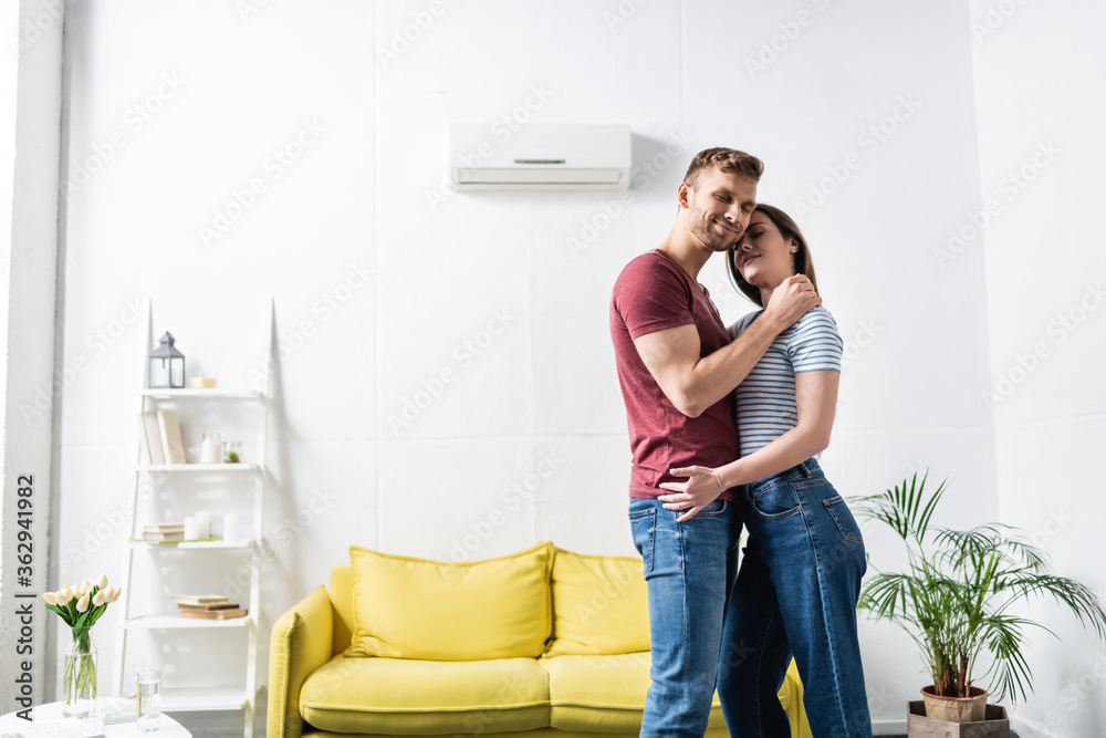 smiling couple hugging at home with air conditioner smiling couple hugging at home with air conditioner