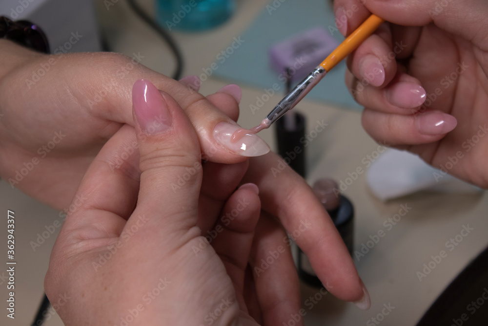 the process of doing manicure. Closeup of hands of professional manicurist, applying nail polish. Concept of doing manicure and fingernails cleaning. beauty concept. Gel polish, shellac the process of doing manicure. Closeup of hands of professional manicurist, applying nail polish. Concept of doing manicure and fingernails cleaning. beauty concept. Gel polish, shellac