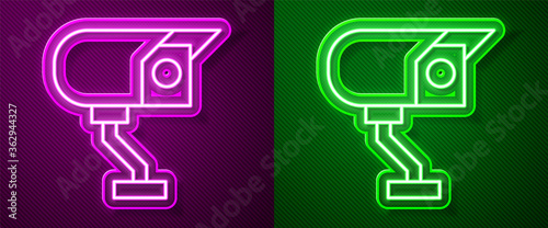 Glowing neon line Security camera icon isolated on purple and green background. Vector.