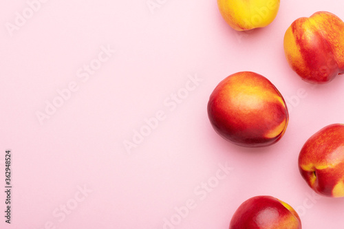 Bright juicy ripe nectarines peaches on a pink background top view. Food organic background. Summer fruits, food for a healthy lifestyle flat lay, copy space.