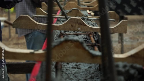 Worker pouring the mixed cement into the wooden block for building the foundation of the house under construction . 