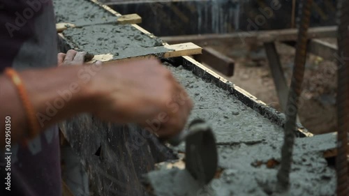 Closeup hand of worker uses the shovel on wet mixed concrete for building the structure of building at construction site