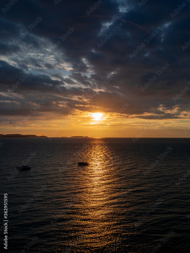 Silhouette of the speed boats coming back into the shore with orange sunset background.