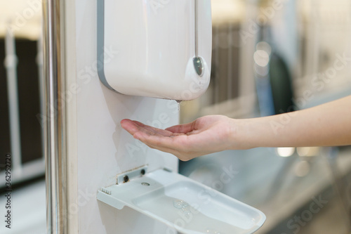 Hands with automatic sanitizer liquid spray machine  touchless dispenser.