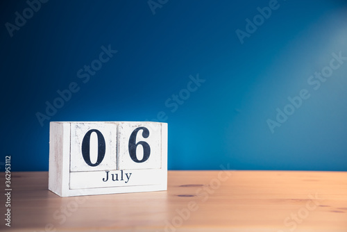 July 6 - white calendar blocks on wooden table against vintage blue background