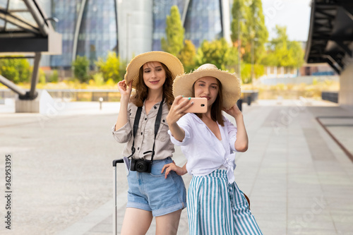 Two beautiful and happy female tourist girls taking a selfie at the train station. © Liliia