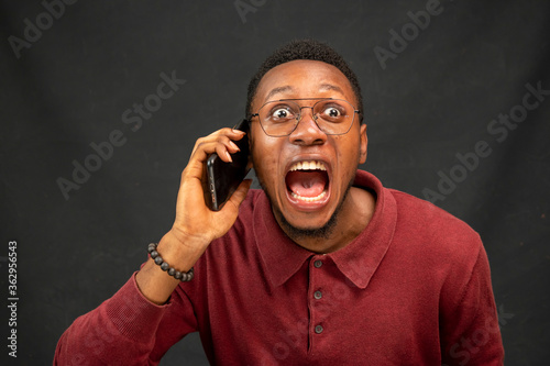 young black man feeling excited while making a phone call, feeling surprised