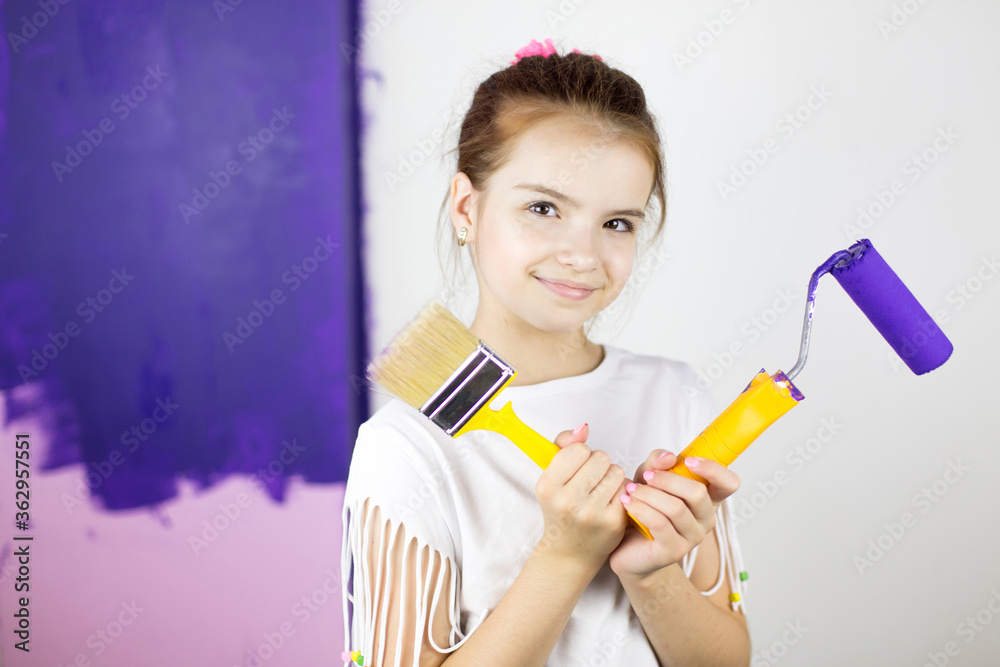 Repair in the apartment. Happy child girl paints the wall Repair in the apartment. Happy child girl paints the wall