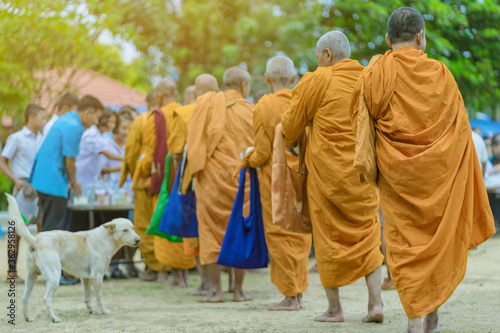 Teachers and students together make merit to give food offerings to a Buddhist monk on important religious days at school.