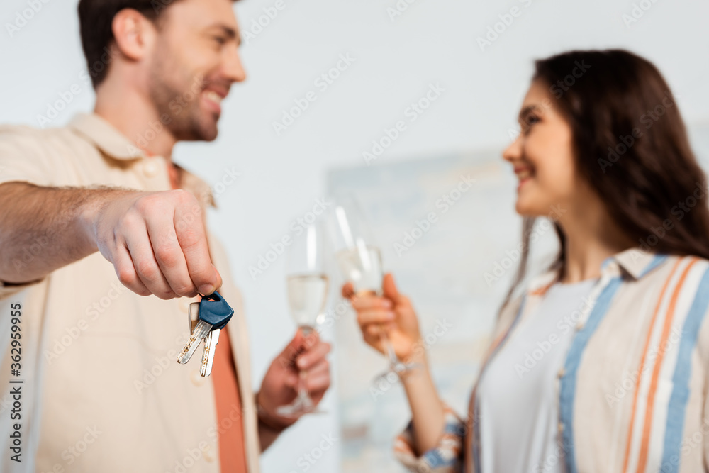 Selective focus of man holding keys of new house and toasting champagne with smiling girl Selective focus of man holding keys of new house and toasting champagne with smiling girl