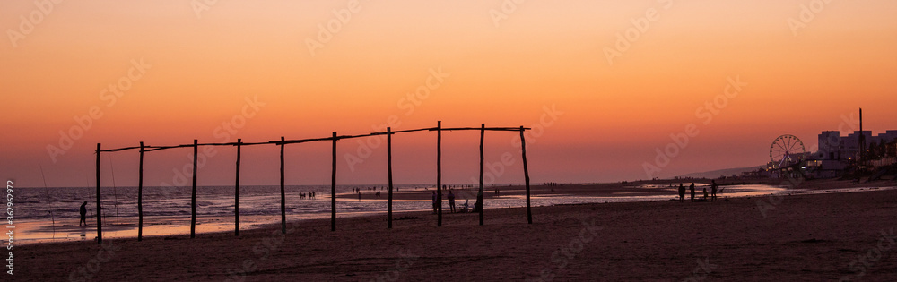 Pescador y cañas puesta de sol playa