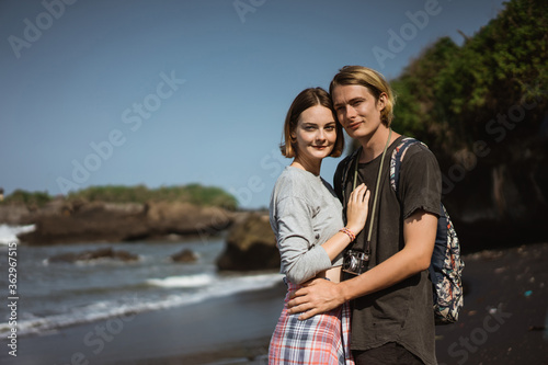 Young couple enjoy a trip together on the beach in the bright sunny day