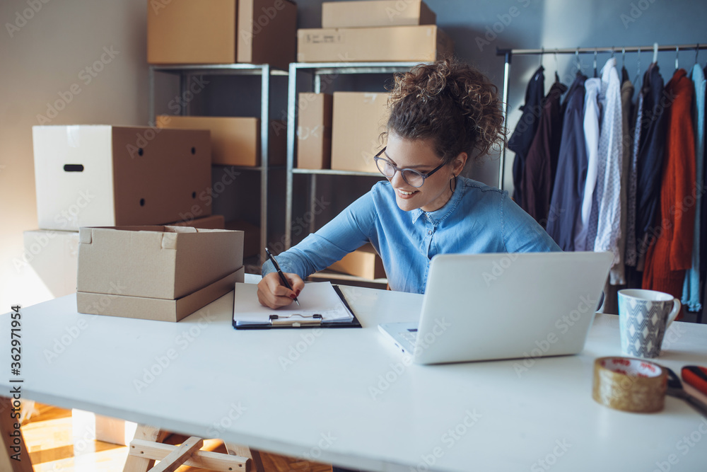 Young smiling entrepreneur working on laptop at her workplace. Confident online business owner working on laptop. Young smiling entrepreneur working on laptop at her workplace. Confident online business owner working on laptop.