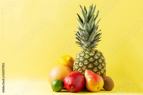 Tropical fruits assortment on yellow background.Pineapple  grapefruit  pear  mango lime lemon and kiwi