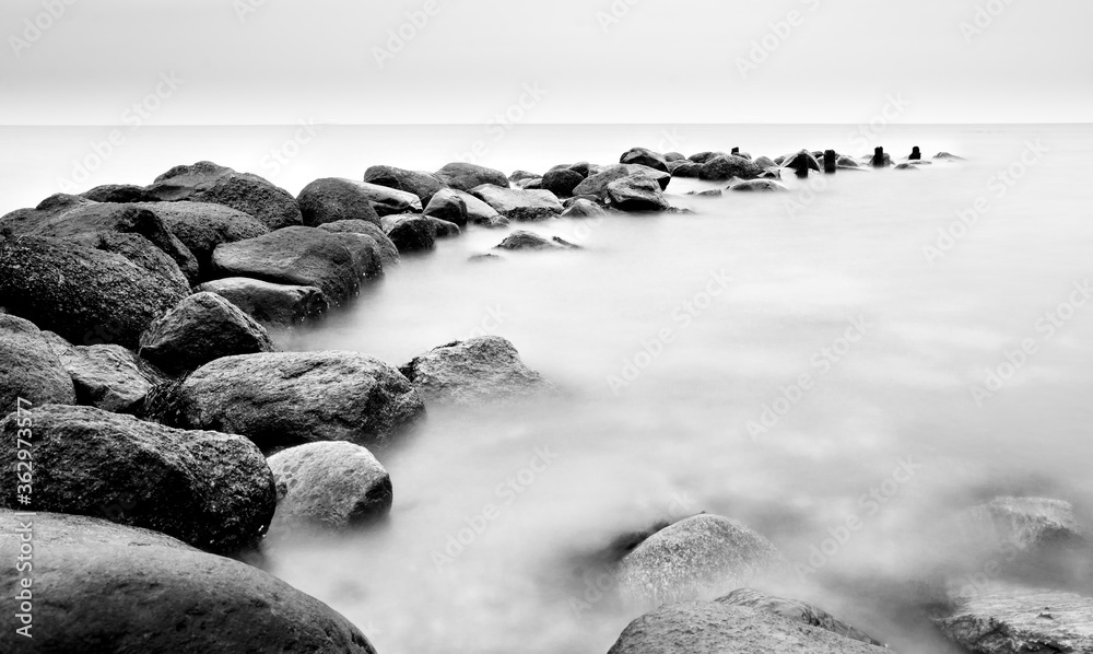 Breakwater Stones in the ocean dark mood for postcards about grief mourning or peaceful and soothing meditation and relaxation Breakwater Stones in the ocean dark mood for postcards about grief mourning or peaceful and soothing meditation and relaxation