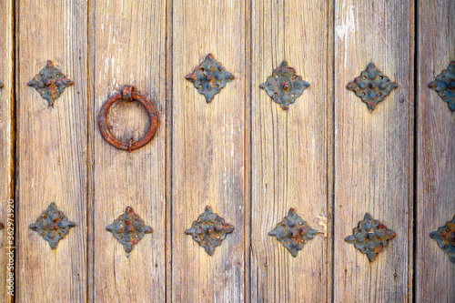 Part of an old wooden door with an iron round handle and rivets