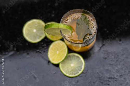 Drink, juice in a glass with a lemon slice, mint and cut lemons around.