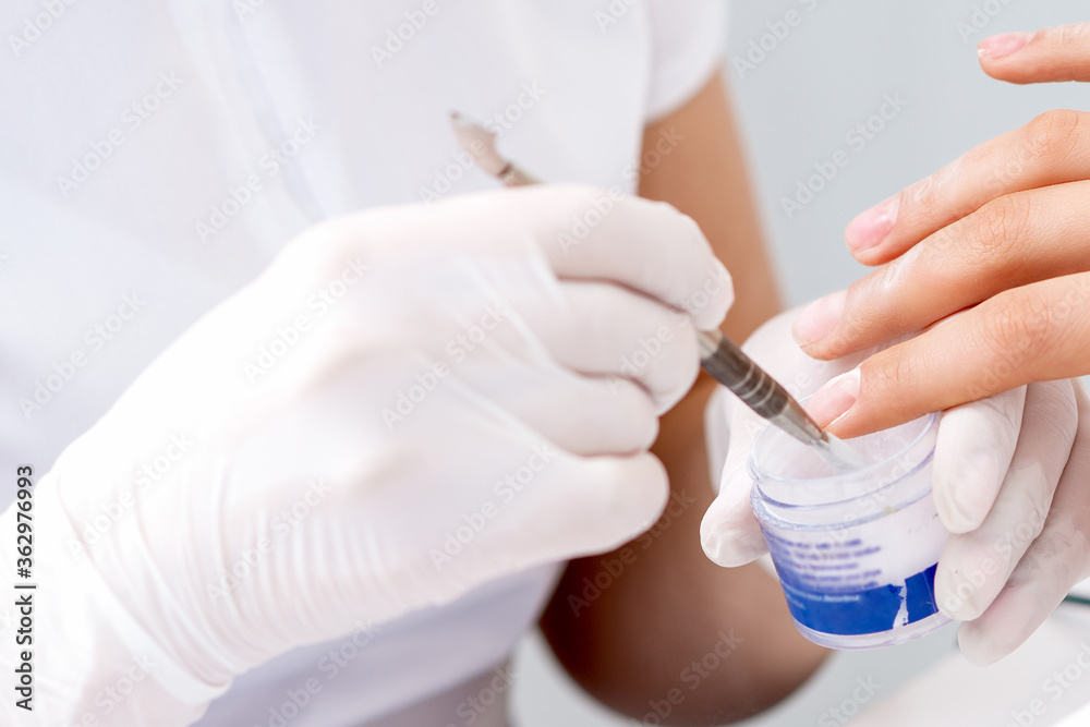 Human hands in protective gloves covering clear varnish on female nails Human hands in protective gloves covering clear varnish on female nails