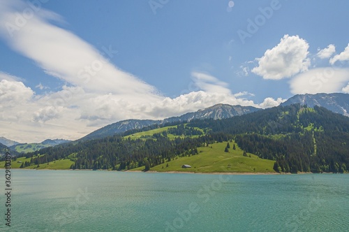 Green hills behind the turquoise lake in Longrin, Switzerland photo