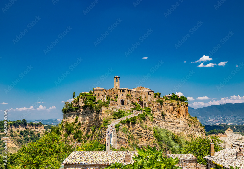 View of the medieval town of Civita di Bagnoregio, located on the top of a spur of tuff rock, in the middle of the valley of the badlands. Connected to the city by a small bridge, mule track.
