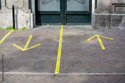 Entrance to a pub with yellow sticker tape reminding people in Dutch to keep social distancing 1,5 meter and in which direction to enter and exit the pub, due to Coronavirus disease (COVID-19)