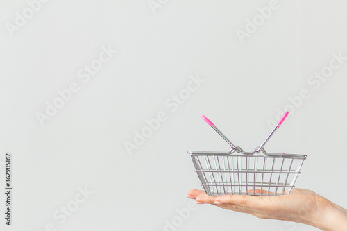 Close-up of a woman's hand holding in the palm of her hand a small metal shopping basket with a pink plastic handle isolated on a white background. concept of shopping. copy space for advertising