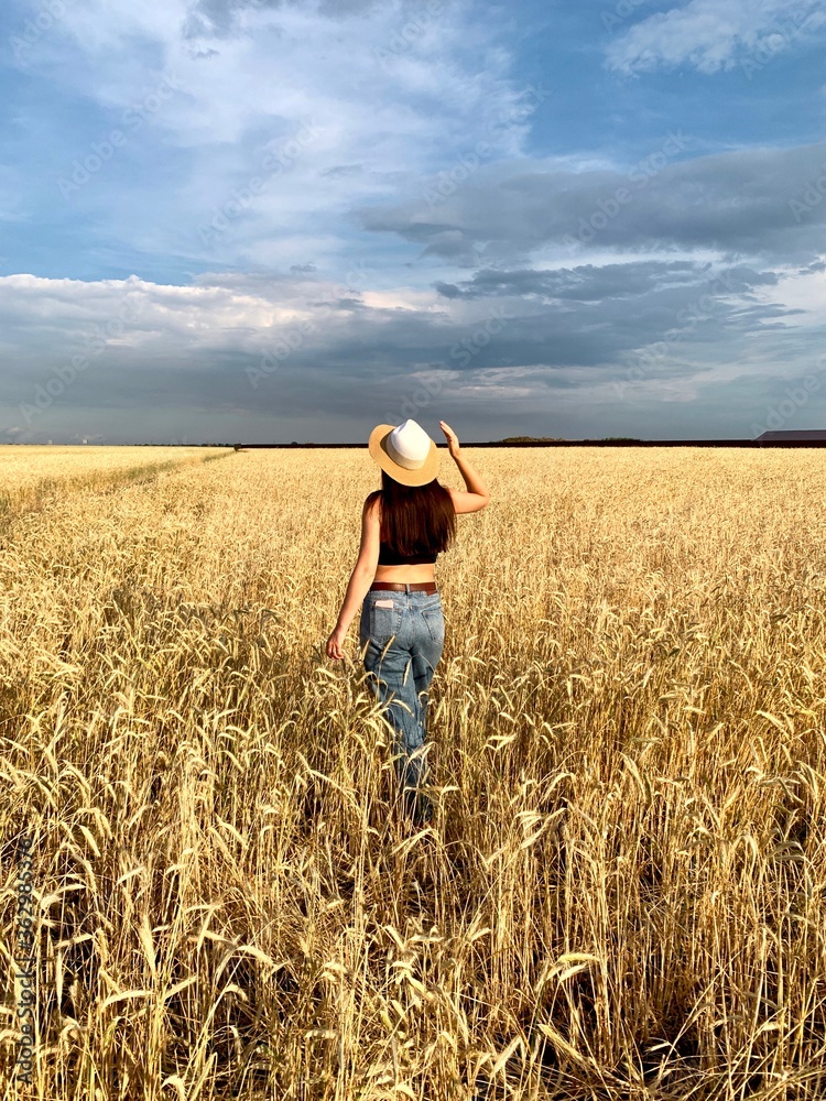 Young happy beautiful slender girl with long hair and a hat in a wheat field. Summer landscape Young happy beautiful slender girl with long hair and a hat in a wheat field. Summer landscape