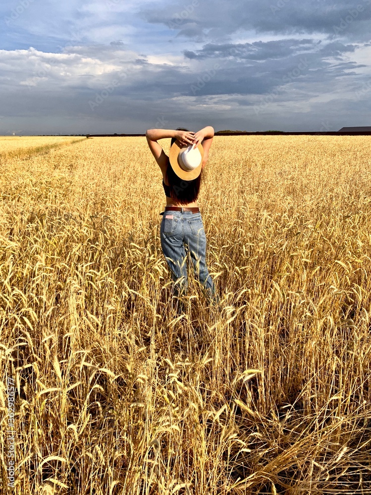 Young happy beautiful slender girl with long hair and a hat in a wheat field. Summer landscape Young happy beautiful slender girl with long hair and a hat in a wheat field. Summer landscape