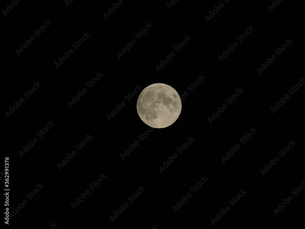 Genova, Italy - 07/05/2020: An amazing photography of the full moon over the city of Genova by night with a great clear and blue sky in the background and some stars. Genova, Italy - 07/05/2020: An amazing photography of the full moon over the city of Genova by night with a great clear and blue sky in the background and some stars.