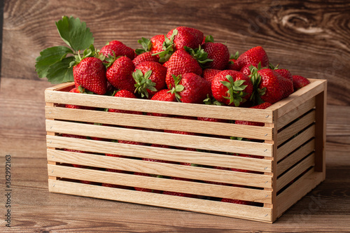 Obraz na płótnie Background from freshly harvested strawberries in wooden box. Wooden clean box with bright, red juicy strawberries. Fresh ripe juice strawberries in box over wooden background. Top view w salonie
