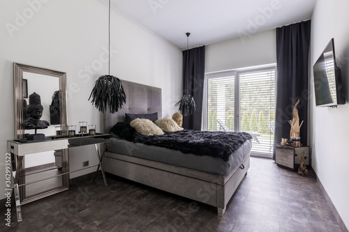 Elegant grey bed with black bedding in bright room interior photo