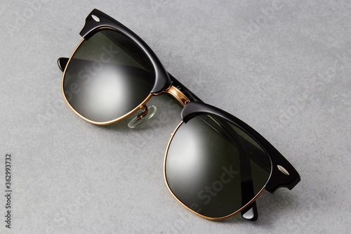 Classic sunglasses with a black frame and black lenses isolated on grey background.