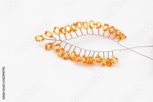 Beaded bonsai tree branch with golden or amber colored leaves. Process of making of jewelry and decorative beaded elements. Leisure and women hobby concept.