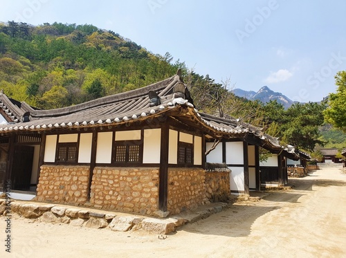 Small Korean buildings near forested mountains under a blue sky at daytime
